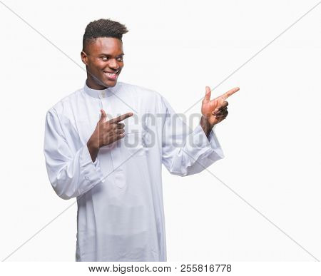 Young arabic african man wearing traditional djellaba over isolated background smiling and looking at the camera pointing with two hands and fingers to the side.