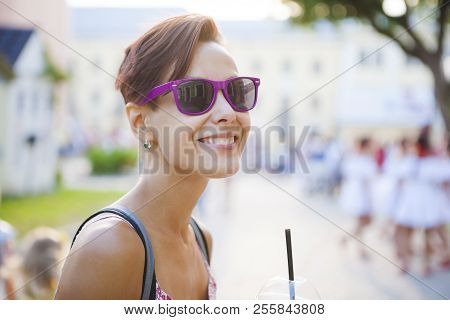 A Girl Drinks A Drink Through A Straw. A Woman In Glasses Drinks Morning Coffee On A City Street. A 