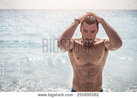 Handsome Muscular Young Man Standing On A Beach, Relaxed, Taking A Bath, Wearing Bathing Suit