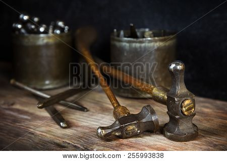 Old Vintage Hammers And Hallmark Steel Punches On A Rustic Wooden Workbench Of A Goldsmith Against A