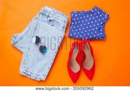 Flat Lay Shot Of Girls Spring Clothing And Accessories On Orange Background. Top View. Bright Femene