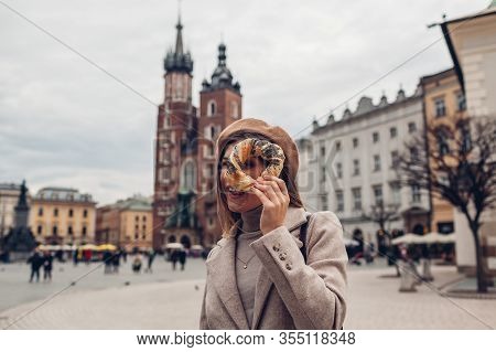 Tourist Woman Holding Bagel Obwarzanek Traditional Polish Cuisine Snack On Market Square In Krakow. 