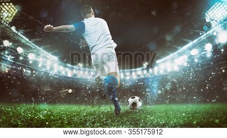 Close Up Of A Soccer Scene At Night Match With Player In A White And Blue Uniform Kicking The Ball W