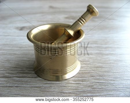 Brass Mortar For Chopping Herbs Or For Spices On A Wooden Background. Close Up.