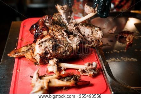 Chev Cuts Juicy Cooked Meat, Separating The Meat From The Bone With A Knife.