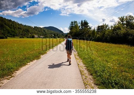 Young Woman With Backpack Hiking Along The Path In The Slovenian Countryside. Bohinj