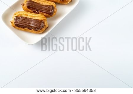 Copy Space. Part Custard Cakes With Chocolate Icing On A White Background.