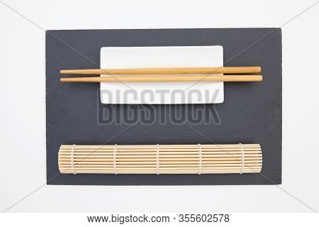 Rectangular Slate Plate With Chopsticks, Ceramic Plate, Bamboo Mat For Sushi On The White Table.