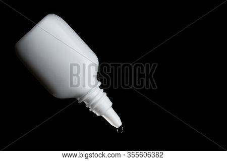 White Bottle For Burying With A Hanging Drop Of Transparent Liquid, Black Background, Isolate, Side 