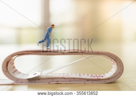 Sport And Fitness Concept. Close Up Of Man Runner Miniature Figure People Running On Measure Tape On