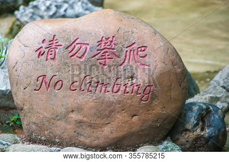 Guilin, China - May 11, 2010: Seven Star Park. Closeup Of Brown Boulder-rock With Sign In Maroon Say