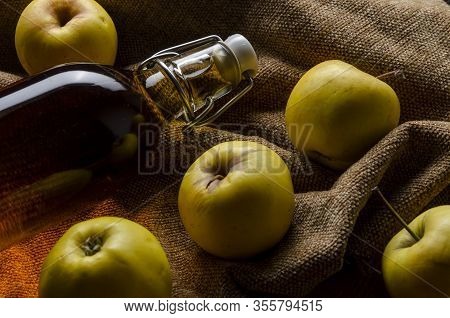 Full Bottle Of Cider With Basket Of Yellow Apples.