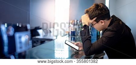 Young Asian Man Feeling Stress, Tired And Headache While Using Chat App On Smartphone At Counter Bar