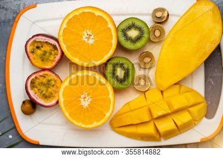 Healthy Vegan Snack Of Raw Tropical Exotic Fruits. Closeup Of Sliced Fresh Mango, Orange, Kiwi, Pass