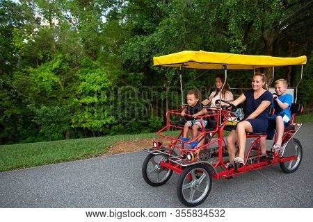 Young happy family riding a double surrey tandem bicycle together. Outdoor summer fun with kids	