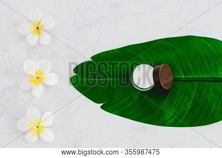 Vegan Natural Beauty, Pot Of Face Cream And Bottle Of Body Lotion On Green Leaves With Monoi Flowers