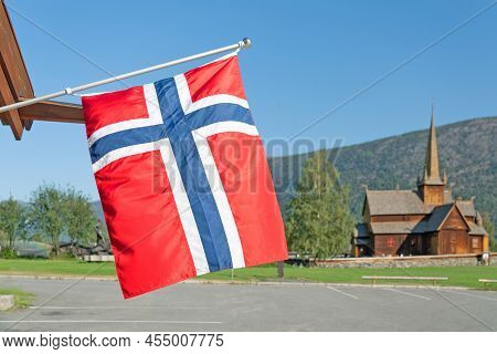 Norwegian Flag And Wooden Church Lomskyrkja In Lom, One Of The Biggest Stave Churches In Norway Date