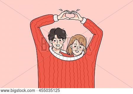 Cute Happy Couple Lovers Wearing One Sweater Make Heart Hand Gesture. Smiling Man And Woman Hug Demo