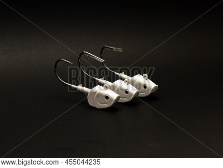 A Row Of Three 2Oz White Shad Jig Heads With Plastic Fishing Hook Tip Cover Isolated On Black Backgr