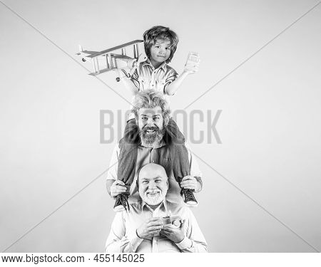 Boy Son With Father And Grandfather With A Toy Airplane Plays On Isolated Background. Family Adventu