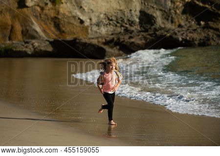 Child Running Through Water Close To Shore Along The Sea Beach. A Boy Runs Along The Sea Coast. Rest
