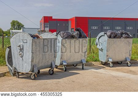Three Metal Dumpster Bins Open Lid Overloaded With Garbage Bags