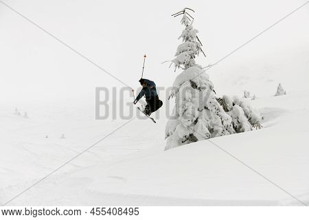 Athlete Skier Masterfully Jumping Over Slopes Of Snow-capped Mountains. Ski Touring, Freeride Extrem