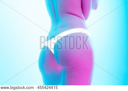 Image Of Slim Female Body, Bottocks In White Underwear Isolated Over Blue Background In Neon Light. 