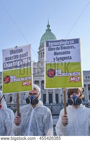 Buenos Aires, Argentina; May 21, 2022: Activists Wearing Biohazard Masks And Suits Hold Signs Agains