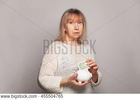 Sed Senior Woman With A Piggy Bank And Us Dollar Money.