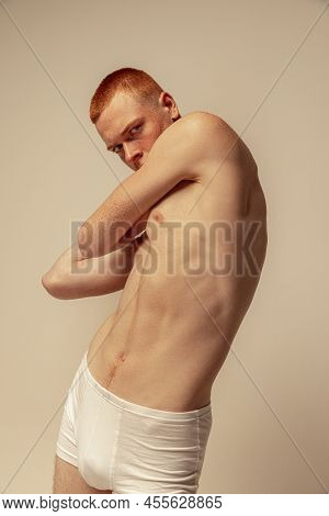 Half-legth Portrait Of Handsome Young Man Posing In White Underwear Isolated Over Grey Studio Backgr