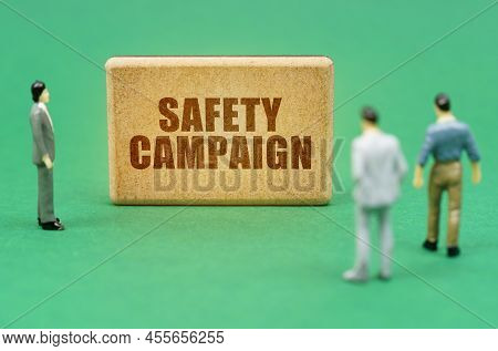 Security And Insurance Concept. On The Green Surface Are Figures Of People And A Sign With The Inscr