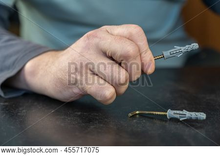 An Adult Male Is Holding An L-type Screw With A Dowel. A Screw With A Hook Is Used For Mounting On W