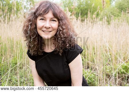 Portrait Of Beautiful Caucasian White Woman With Brown Curly Hair Looking At Camera And Smiling. Hap