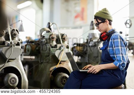 Serious Busy Watch Factory Worker In Beanie Hat And Ear Protectors On Neck Sitting On Stool In Indus