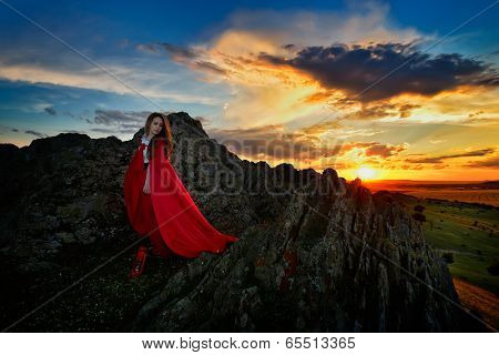 beautiful woman with red cloak in the sunset light in spring