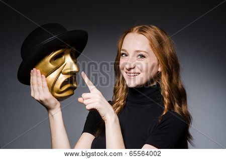 Redhead woman iwith mask in hypocrisy consept against grey background