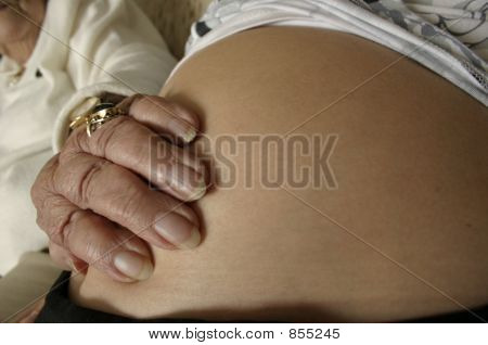 vecchia mano sul ventre della donna incinta