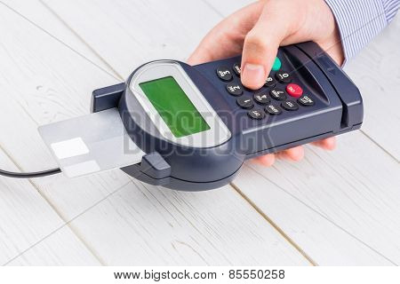 Man entering his pin on terminal on a wooden table