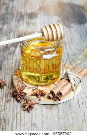 Golden honey with honeystick. cinnamon and anise stars on wooden table