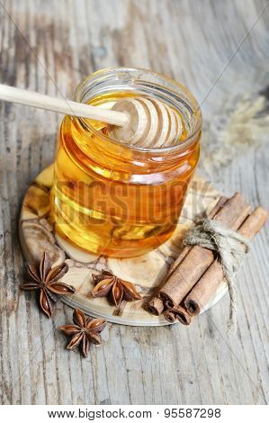 Golden honey with honeystick. cinnamon and anise stars on wooden table