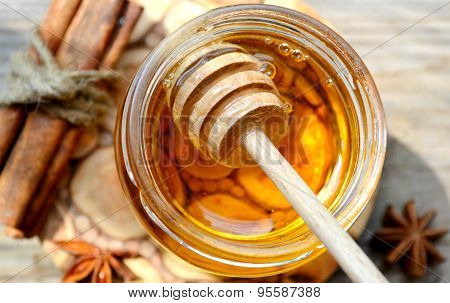 Golden honey with honeystick. cinnamon and anise stars on wooden table