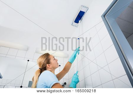Cleaning Service Woman Cleaning The Ceiling Of The Bathroom With Mop At Home
