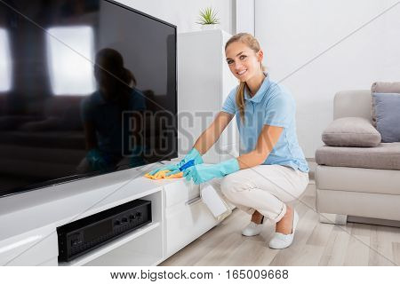 Young Happy Woman Cleaning The Furniture Of Living Room At Home