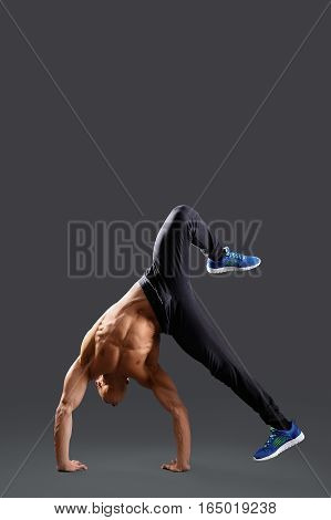 Life in motion. Shirtless male breakdancer showing some moves on grey background copyspace