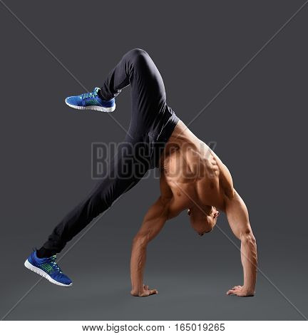 Never resting. Muscular young man doing a handstand shirtless showing off his strong body