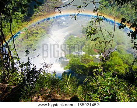 Vew of the water falls in Cataratas del Iguazu park, with a blue sky and a lot of water in the air, misty, rainow.