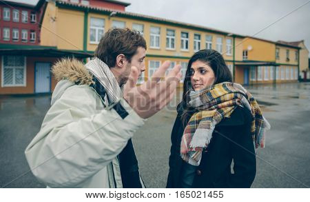 Portrait of dissapointed woman listening arguments of young man during a hard quarrel outdoors. Couple relationships and problems concept.