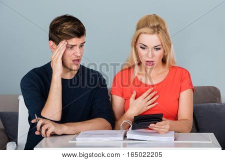 Worried Bankrupt Couple In Finance Trouble Calculating Their Money And Bills On Desk At Home