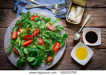 fresh mix of lettuce salad with tomato and a can of sardines in olive oil